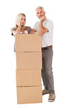 Happy couple leaning on pile of moving boxes