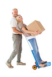 Happy couple having fun with trolley and moving box