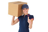 Happy delivery woman holding cardboard box showing thumbs up