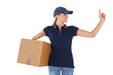 Happy delivery woman holding cardboard box and pointing up