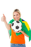 Football fan holding ball and wearing brazil flag