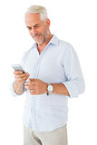 Smiling man sending a text message