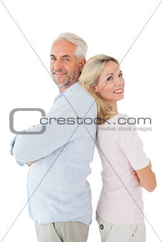 Smiling couple standing leaning backs together