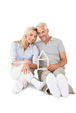 Happy couple sitting and holding house outline
