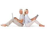 Happy couple sitting using laptop and tablet pc