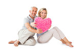 Happy couple sitting and holding heart pillow