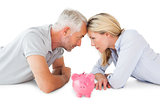 Happy couple lying with piggy bank
