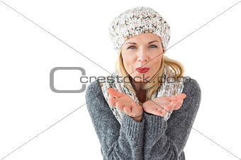 Smiling woman in winter fashion blowing at camera