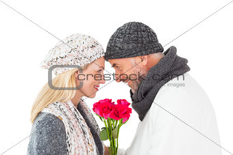 Smiling couple in winter fashion posing with roses