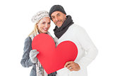 Smiling couple in winter fashion posing with heart shape