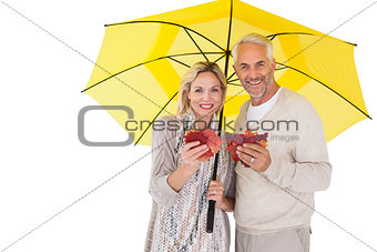 Smiling couple showing autumn leaves under umbrella