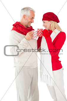 Smiling couple in winter fashion toasting with mugs