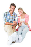 Attractive young couple sitting holding a house outline