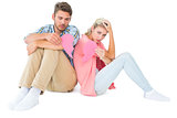Attractive young couple sitting holding two halves of broken heart