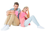 Attractive young couple sitting holding two halves of broken heart