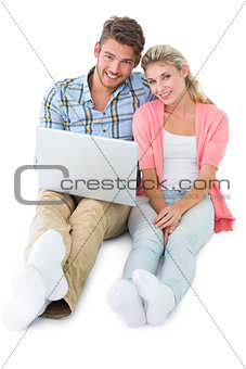 Attractive young couple sitting using laptop