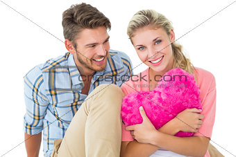 Attractive young couple sitting holding heart cushion