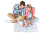 Attractive young couple sitting looking at blueprint