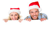 Festive couple smiling from behind poster