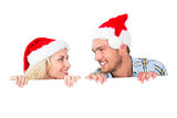 Festive couple smiling from behind poster