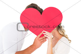 Attractive young couple kissing behind large heart