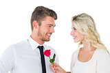 Handsome man smiling at girlfriend holding a rose