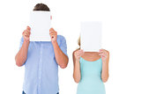Young couple holding pages over their faces