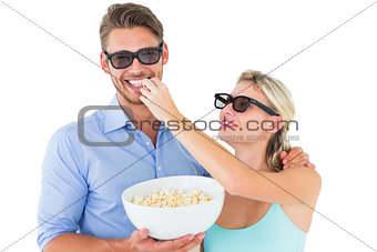 Happy young couple wearing 3d glasses eating popcorn