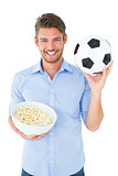 Handsome young man holding ball and popcorn