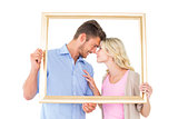 Attractive young couple holding picture frame