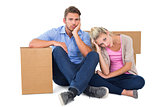 Unhappy young couple sitting beside moving boxes