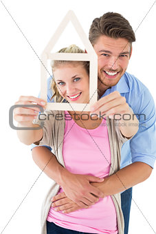 Young couple hugging and holding house outline