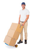 Happy delivery man pushing trolley of boxes