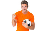 Excited man in orange cheering holding football
