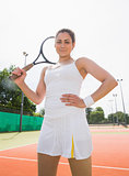 Pretty tennis player holding racket smiling at camera