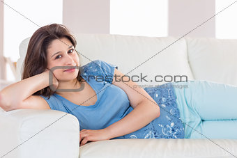 Pretty brunette smiling at camera on the couch