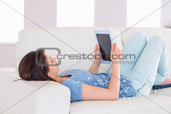 Pretty brunette using her tablet pc on the couch
