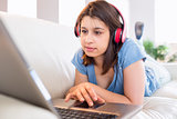 Pretty brunette using laptop listening to music on the couch