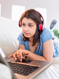 Pretty brunette using laptop listening to music on the couch
