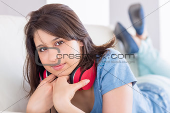 Pretty brunette wearing earphones around neck on the couch