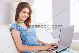 Pretty brunette relaxing on the couch using laptop