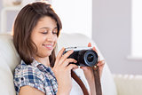 Pretty brunette looking at retro camera on couch