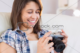 Pretty brunette looking at retro camera on couch