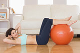 Fit brunette doing sit ups with exercise ball