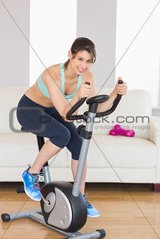 Fit brunette working out on exercise bike