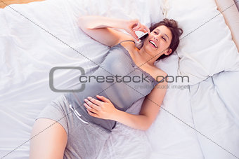 Beautiful brunette lying on bed talking on phone