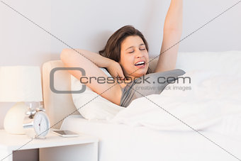 Beautiful brunette yawning and stretching in her bed
