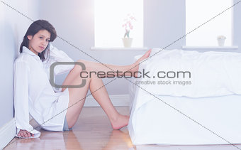 Sexy brunette sitting on floor beside bed