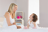 Mother and daughter looking at each other on bed