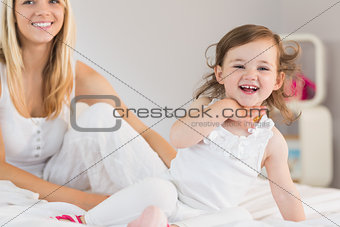 Mother and daughter sitting on bed at home